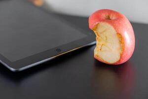 Bitten Apple Next to Tablet on Black Surface photo