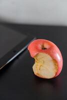Bitten Red Apple Next to Tablet photo