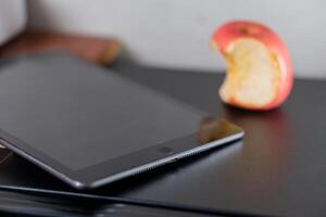 Tablet and Apple on Black Surface photo