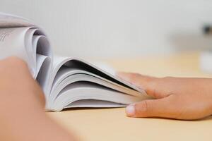 Close-Up of Hands Flipping Through a Book on Desk photo