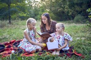 a mother and her two daughters read the holy bible and pray at an Easter picnic photo