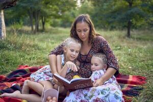 a mother and her two daughters read the holy bible and pray at an Easter picnic photo