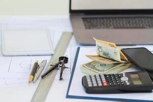 Engineers and Foreman are calculating workers' expenses and overtime to pay workers compensation and overtime each month. Foreman holds cash in hand to pay workers as compensation photo