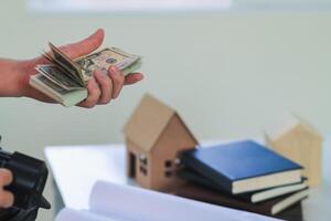 Engineers and Foreman are calculating workers' expenses and overtime to pay workers compensation and overtime each month. Foreman holds cash in hand to pay workers as compensation photo
