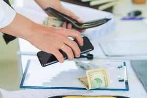 Engineers and Foreman are calculating workers' expenses and overtime to pay workers compensation and overtime each month. Foreman holds cash in hand to pay workers as compensation photo