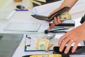 Engineers and Foreman are calculating workers' expenses and overtime to pay workers compensation and overtime each month. Foreman holds cash in hand to pay workers as compensation photo