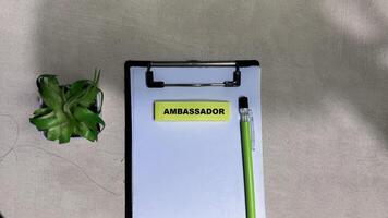 Concept of Ambassador write on sticky notes isolated on Wooden Table. photo
