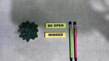 Concept of Be Open Minded write on sticky notes isolated on Wooden Table. photo