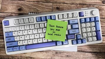 Concept of Think Before You Post on Social Media write on sticky notes isolated on Wooden Table. photo