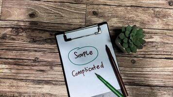 Concept of Simple or Complicated write on paperwork isolated on wooden background. photo
