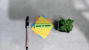 Concept of Keep it Mind write on sticky notes isolated on Wooden Table. photo