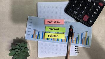 Concept of National Pension Scheme write on sticky notes isolated on Wooden Table. photo