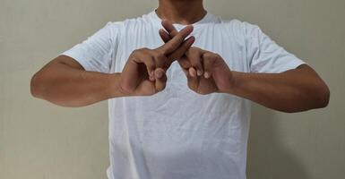 Young man showing fingers gestures, having fun, leading pleasant in american sign language photo