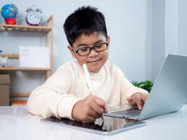 Asian student boy using computer and tablet learning. Educational of tech concept, Staying at home, Presenting a modern educational way of life. Virtual internet online class from school teacher. photo