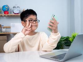 Asian student boy using computer and phone learning. Educational of tech concept, Staying at home, Presenting a modern educational way of life. Virtual internet online class from school teacher. photo