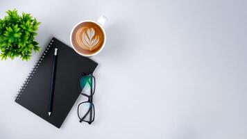 Top view white workspace office desk with office supplies. Flat lay work table with black notebook, Green leaf and coffee cup, Copy space for your advertising content. photo