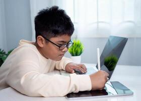 Asian student boy using computer and tablet learning. Educational of tech concept, Staying at home, Presenting a modern educational way of life. Virtual internet online class from school teacher. photo