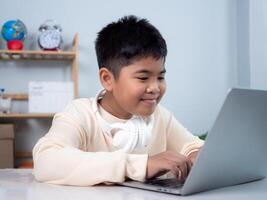 Educational of tech concept, Staying at home, Little Asian boy student using computer laptop learning. Presenting a modern educational way of life. Virtual internet online class from school teacher. photo