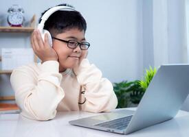 Asian student boy using headphones and computer learning. Educational of tech concept, Staying at home, Presenting a modern educational way of life. Virtual internet online class from school teacher. photo