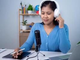 Woman talking into microphone on stand, Content creator concept, Lead on-line communication, Discuss topic, looks at notebook screen, Engaged in streaming, Virtual meeting event, Podcast, Webinar. photo