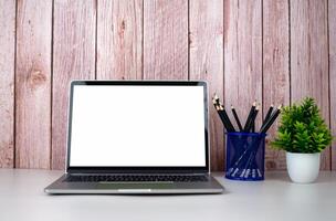 Laptop with blank screen on white table and office supplies on wooden background. Space for copying your text. Workspace and copy space. Desk with office supplies. photo