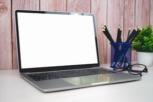 Laptop with blank screen on white table and office supplies on wooden background. Space for copying your text. Workspace and copy space. Desk with office supplies. photo