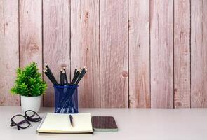 Workspace mock up white table top with vintage notebook, Pencils and green houseplant. Copy space desk with copy space for products display montage. Minimalist white workplace with supplies. photo