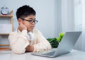 Educational of tech concept, Staying at home, Little Asian boy student using computer laptop learning. Presenting a modern educational way of life. Virtual internet online class from school teacher. photo