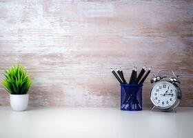 Stylish minimalist white table workplace with supplies, House plant. White desk table with copy space, Supplies and alarm clock. Workspace and copy space. Copy space for product display montage. photo