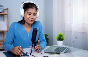 Content creator concept, Woman talking into microphone on stand, Lead on-line communication, Discuss topic, looks at notebook screen, Engaged in streaming, Virtual meeting event, Podcast, Webinar. photo