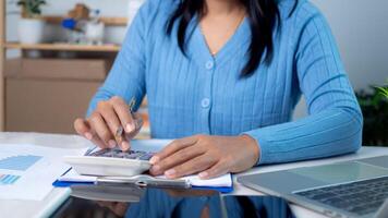 Businesswoman hand working with finances about cost and calculator and laptop with tablet on desk at office in morning light, Business accounting concept, Calculating or checking balance. photo