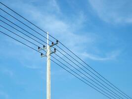 Reinforced concrete pillar with high-voltage wires against a clear blue sky. Transmission of electricity by wires over long distances. Electricity power lines against a clear sky. photo