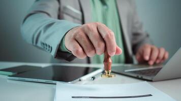Businessman hand stamping with approved stamp on text approved document at desk, Validates and manages business documents and agreements, Approval stamp, Signing on business partner paper to success. photo