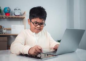 Little Asian boy student using computer laptop learning. Educational of tech concept, Staying at home, Presenting a modern educational way of life. Virtual internet online class from school teacher. photo