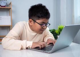 Little Asian boy student using computer laptop learning. Educational of tech concept, Staying at home, Presenting a modern educational way of life. Virtual internet online class from school teacher. photo