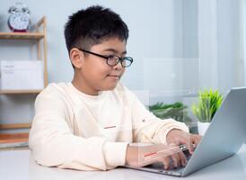 Asian boy student using computer laptop learning. Educational of tech concept, Staying at home, Presenting a modern educational way of life. Virtual internet online class from school teacher. photo
