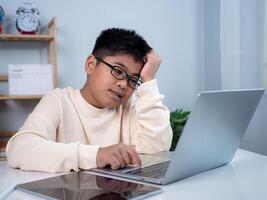Boy using computer for learning and stressed about online learning, Virtual internet online class from school teacher by remote meeting, Homeschooling and education concept, online education concept. photo