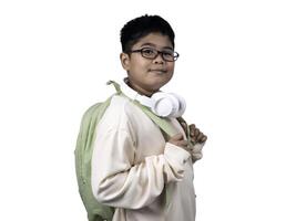 Portrait of boy in casual clothes carry a green bag and white headphones isolated on a white background, The concept of education and way of life. Cute boy posing in casual clothes with clipping part. photo