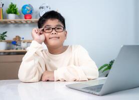Asian boy student using computer laptop learning. Educational of tech concept, Staying at home, Presenting a modern educational way of life. Virtual internet online class from school teacher. photo