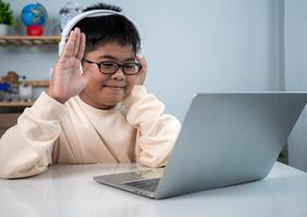 Little Asian boy student using computer laptop learning. Educational of tech concept, Staying at home, Presenting a modern educational way of life. Virtual internet online class from school teacher. photo