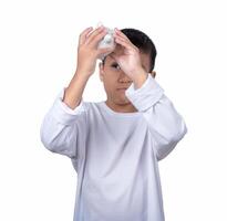 A boy wearing a white shirtis holding and trying to open a white piggy bank The concept of saving for the future. photo