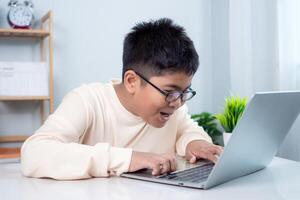 Asian boy student using computer laptop learning. Educational of tech concept, Staying at home, Presenting a modern educational way of life. Virtual internet online class from school teacher. photo
