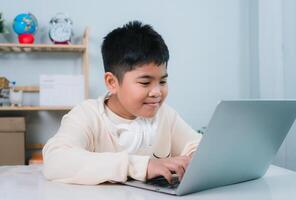 Asian boy student using computer laptop learning. Educational of tech concept, Staying at home, Presenting a modern educational way of life. Virtual internet online class from school teacher. photo
