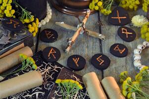 Mystic still life with old scrolls, black runes and witchy ritual objects on wooden altar table. Occult, esoteric, wicca, Halloween and gothic concept. photo