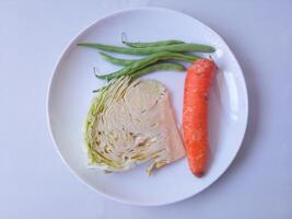 cabbage, carrots, green beans, red onion garlic on a plate and isolate on white. healthy food concept. diet menu concept photo