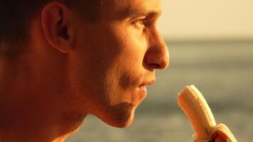 Man Banana Eating Sunset Beach. A man eats a banana while looking out at a beach sunset. video
