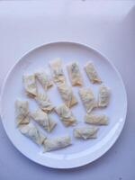 Piscok or banana chocolate are traditional snacks from Indonesia. made of fried banana wrapped in spring roll skin and assorted melted toppings on a white plate before frying photo