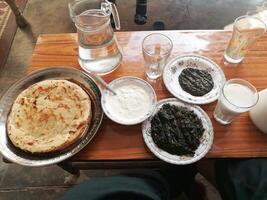 A delightful spread features savory mutton, tender chicken, flavorful daal, and a steaming cup of tea, complemented by an assortment of dry fruits for a touch of sweetness and texture. photo