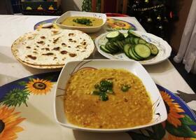 A delightful spread features savory mutton, tender chicken, flavorful daal, and a steaming cup of tea, complemented by an assortment of dry fruits for a touch of sweetness and texture. photo