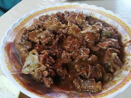 A delightful spread features savory mutton, tender chicken, flavorful daal, and a steaming cup of tea, complemented by an assortment of dry fruits for a touch of sweetness and texture. photo